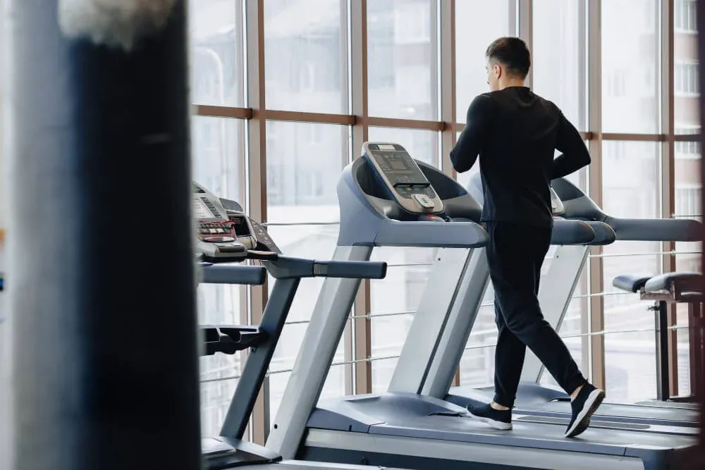 Indonesian runners doing a controlled treadmill workout inside a simple well-ventilated gym in Kalimantan, relaxed candi